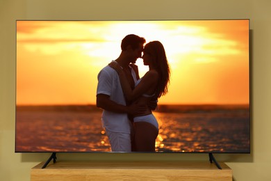 Image of Tv near beige wall. Romantic movie on screen