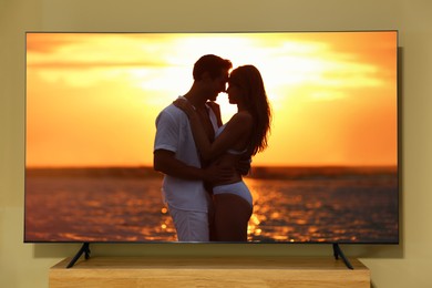 Tv near beige wall. Romantic movie on screen