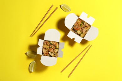 Photo of Noodle wok with chopsticks and lime slices on yellow background, flat lay