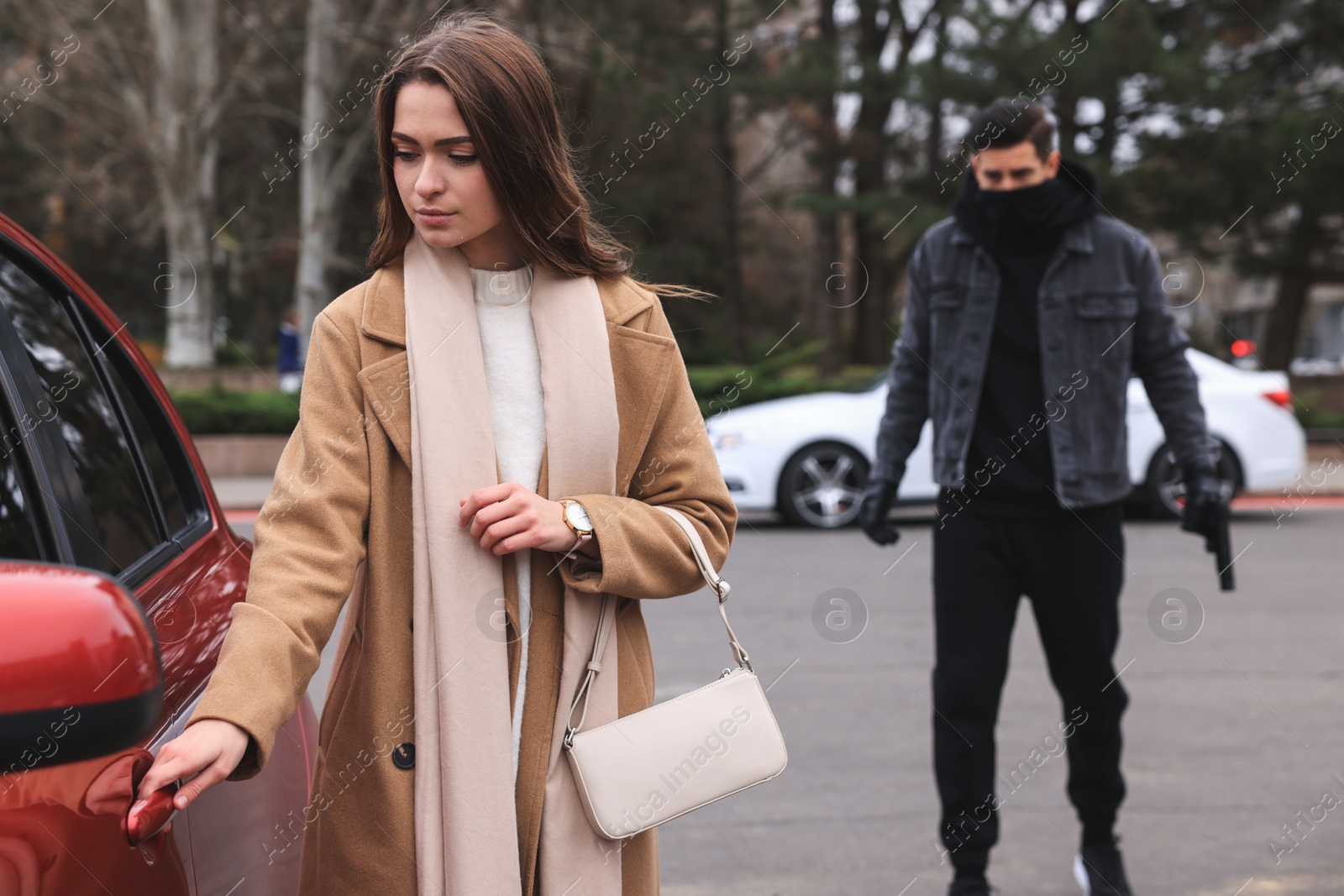 Photo of Man with gun stalking young woman on parking lot outdoors