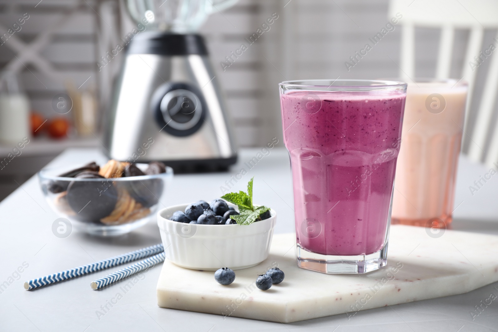 Photo of Tasty milk shake and blueberries on white table