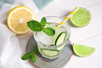 Photo of Glass of refreshing cucumber water with mint on white wooden table