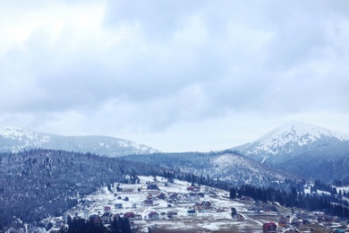 Photo of Winter landscape with mountain village near conifer forest