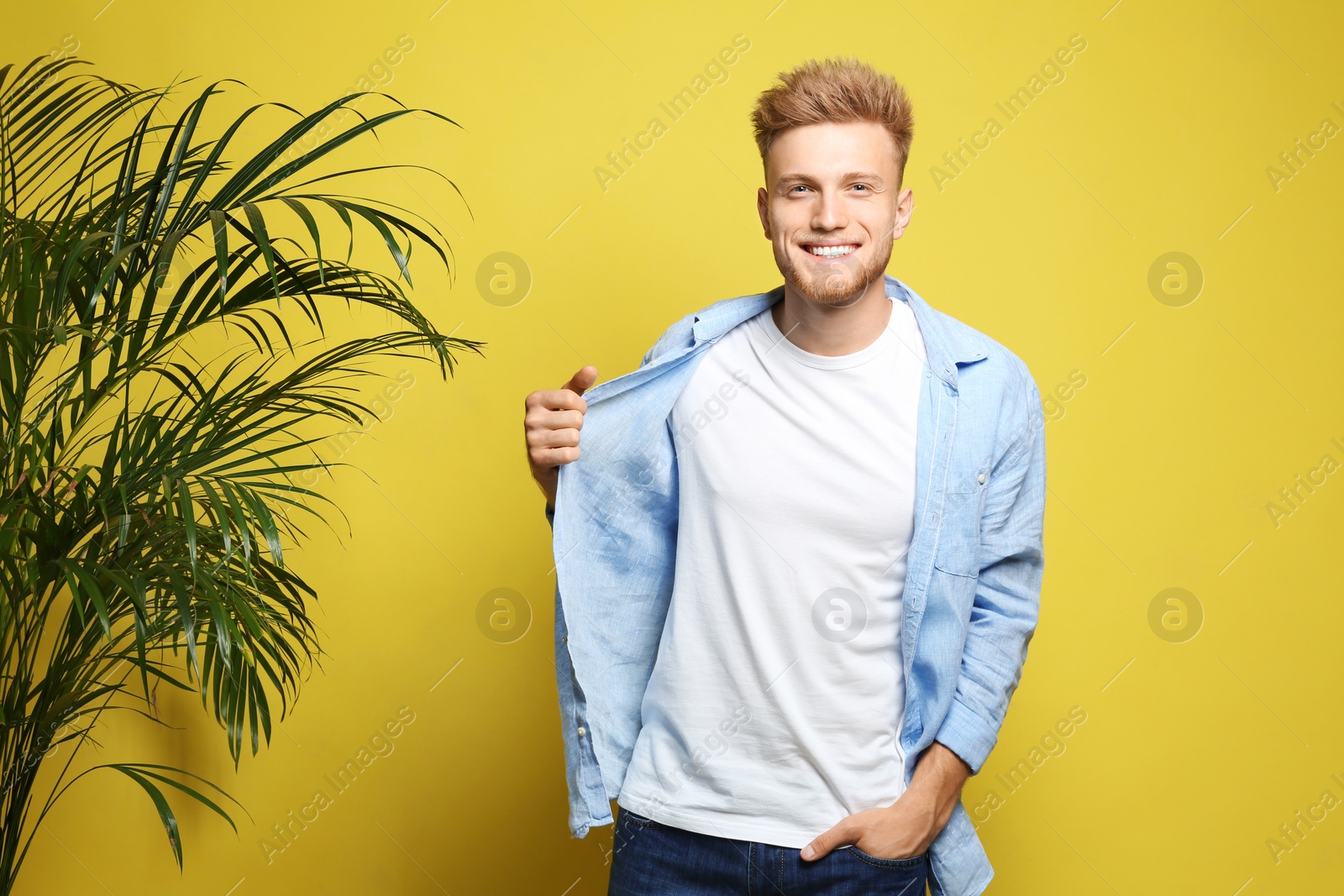 Photo of Young man wearing blank t-shirt on yellow background. Mockup for design