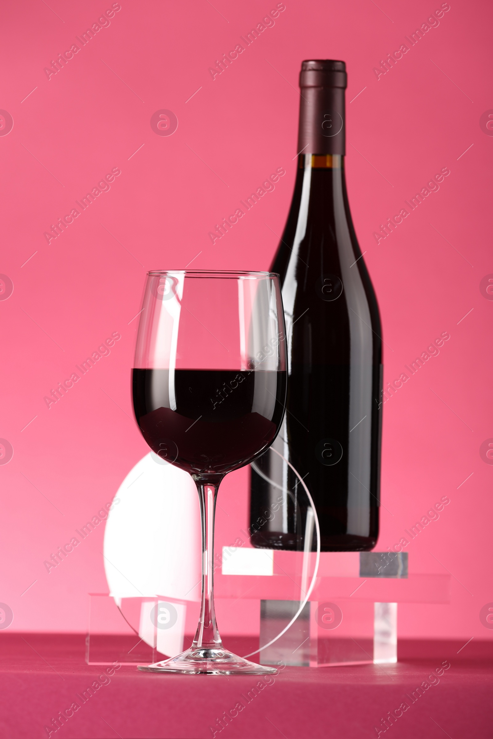 Photo of Stylish presentation of delicious red wine in bottle and glass on pink background