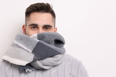 Man in warm scarf on light background. Space for text