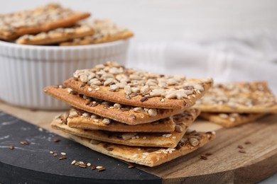 Photo of Cereal crackers with flax, sunflower and sesame seeds on board, closeup