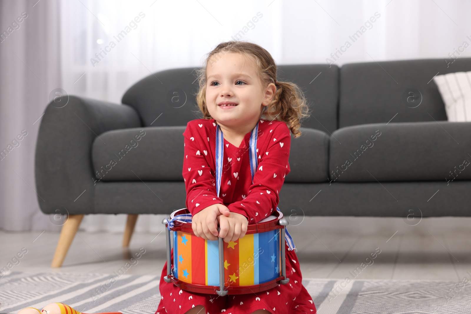 Photo of Little girl playing toy drum at home