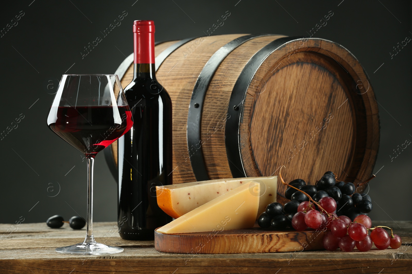 Photo of Winemaking. Composition with tasty wine and barrel on wooden table against gray background