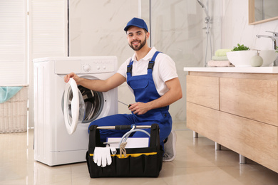 Photo of Repairman with toolbox near washing machine in bathroom
