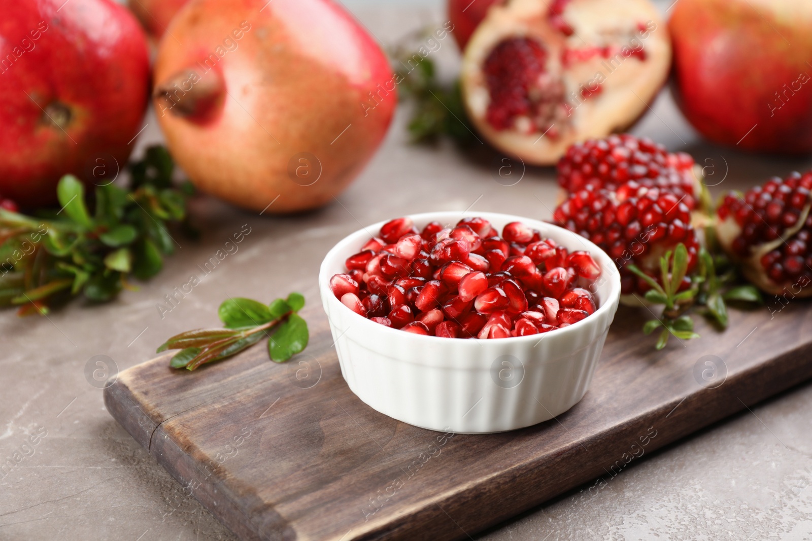 Photo of Delicious ripe pomegranate kernels in bowl on grey table