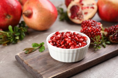 Photo of Delicious ripe pomegranate kernels in bowl on grey table