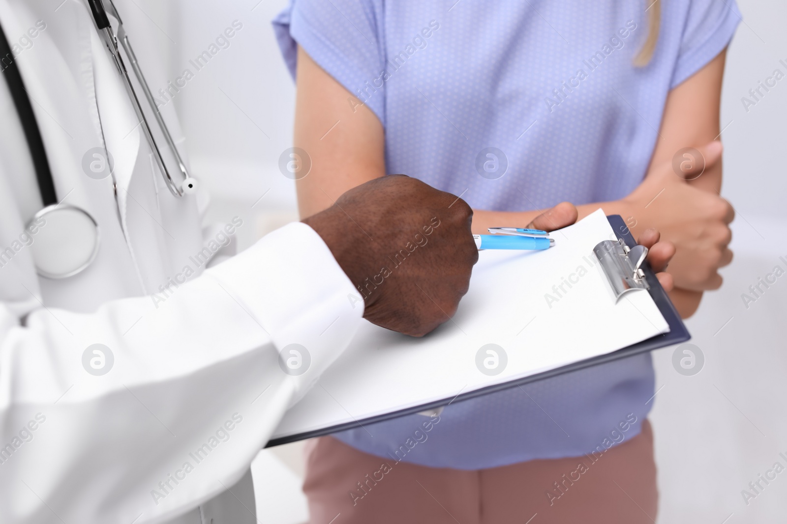 Photo of Young African-American doctor consulting patient in modern hospital