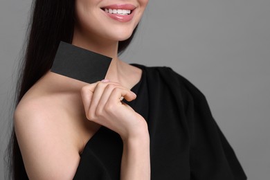 Photo of Woman holding blank business card on grey background, closeup. Space for text