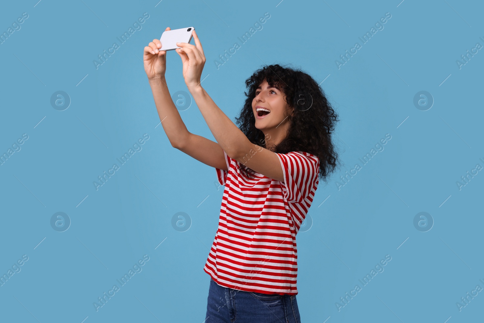 Photo of Beautiful young woman taking selfie on light blue background