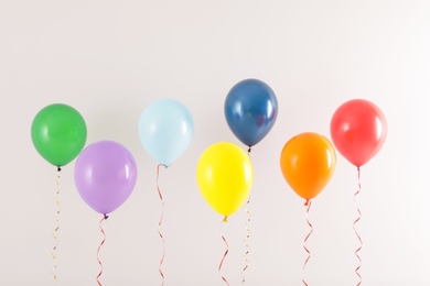 Photo of Different bright balloons on light background. Celebration time