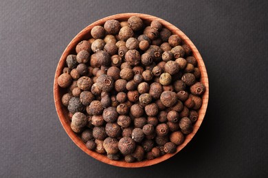 Photo of Bowl of allspice pepper grains on grey background, top view