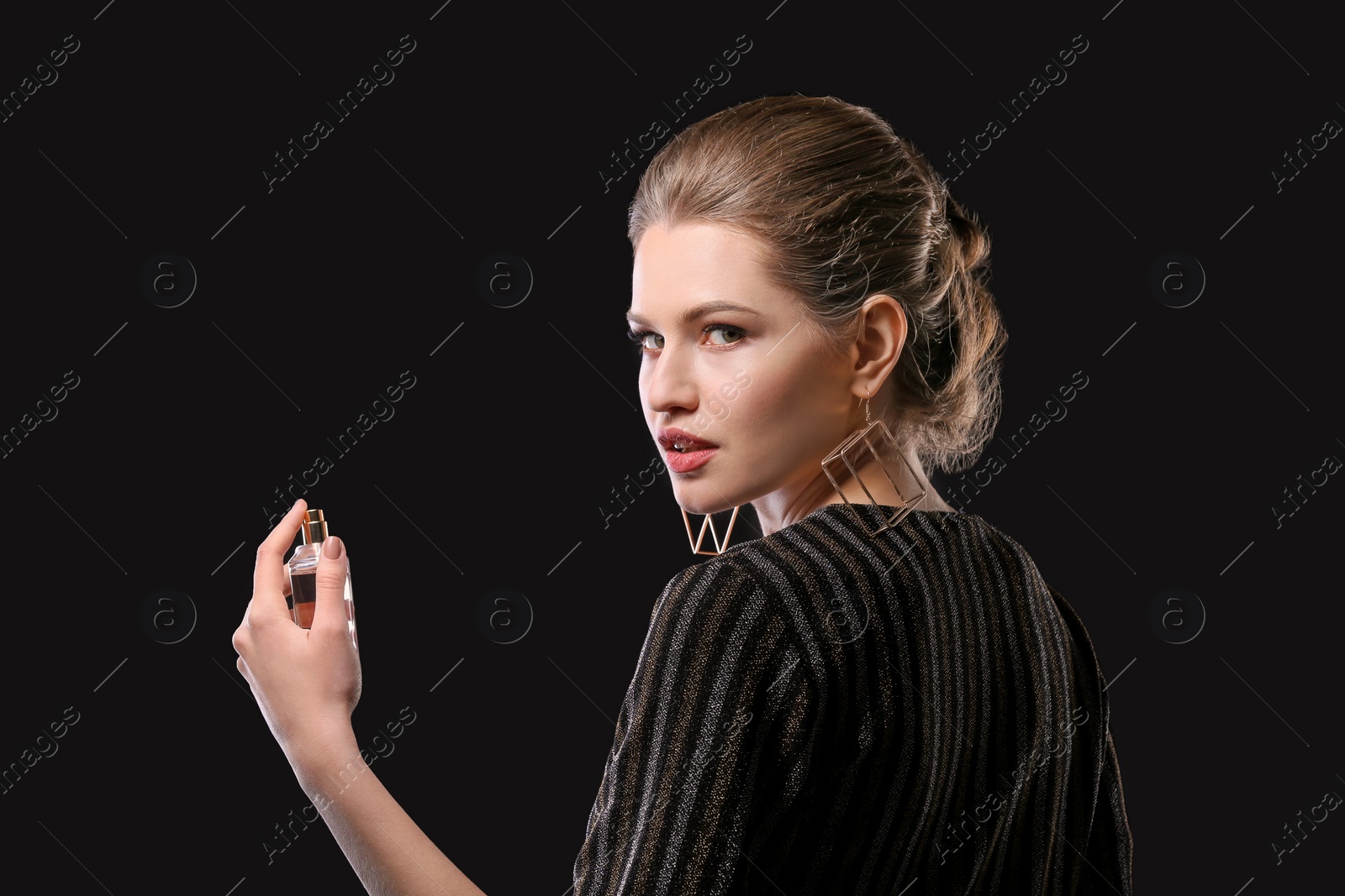 Photo of Beautiful young woman with bottle of perfume on black background