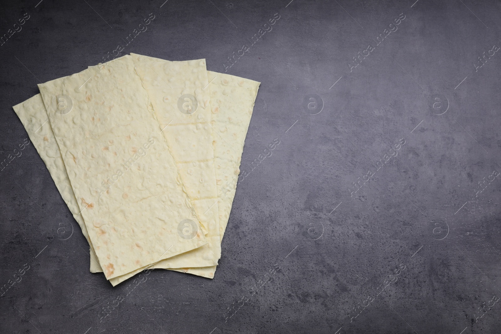 Photo of Delicious Armenian lavash on dark table, top view. Space for text