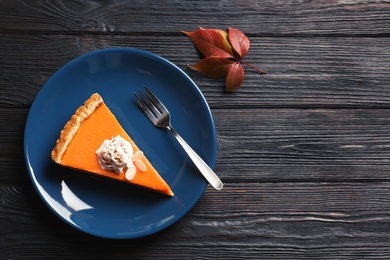 Photo of Flat lay composition with piece of fresh delicious homemade pumpkin pie and space for text on wooden background