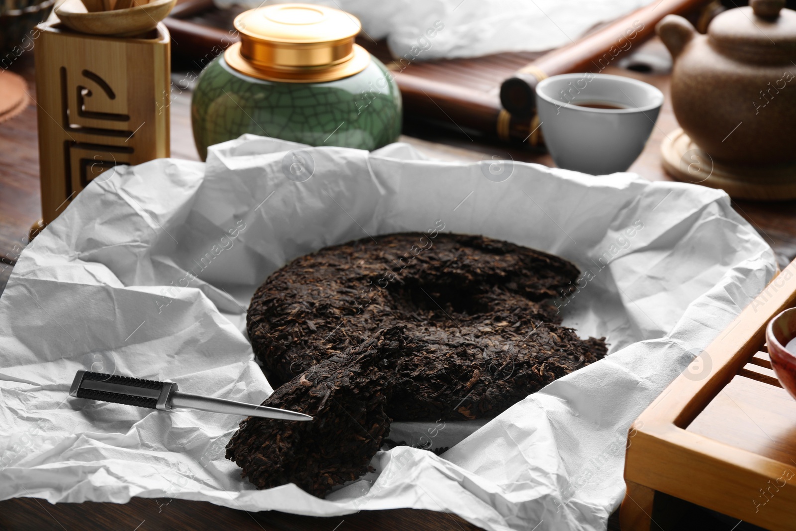 Photo of Broken disc shaped pu-erh tea and knife on wooden table