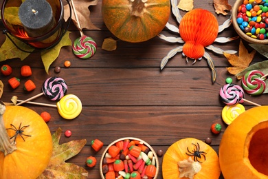 Photo of Flat lay composition with pumpkin head Jack lantern and Halloween treats on wooden background. Space for text