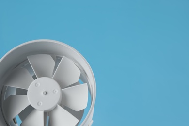 Photo of Modern electric fan on light blue background. Space for text