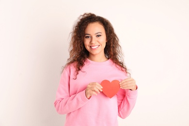 Photo of African-American woman with paper heart on white background