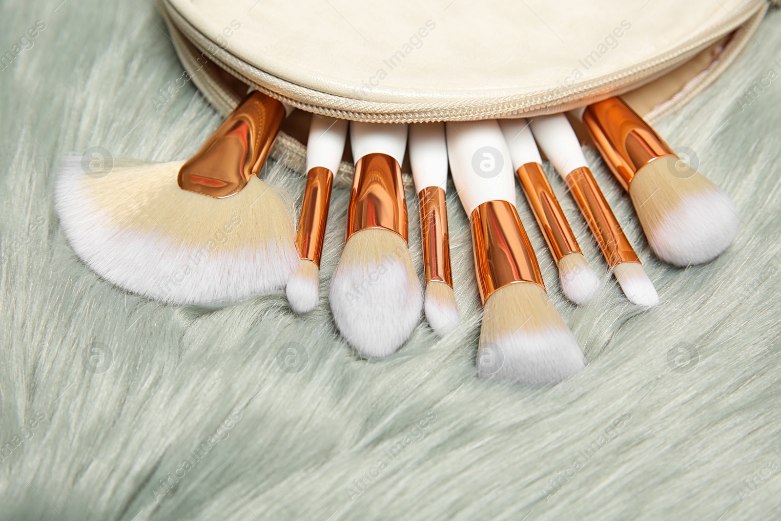 Photo of Bag with set of makeup brushes on furry fabric