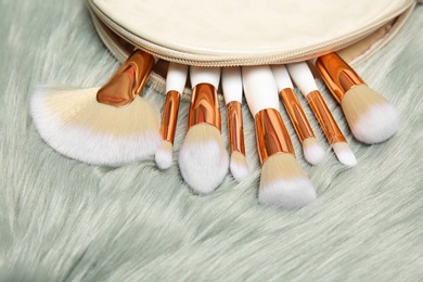 Bag with set of makeup brushes on furry fabric