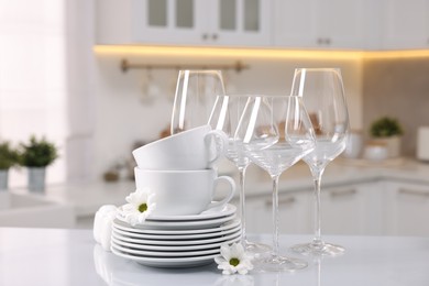 Photo of Set of clean dishware, glasses and flowers on table in kitchen