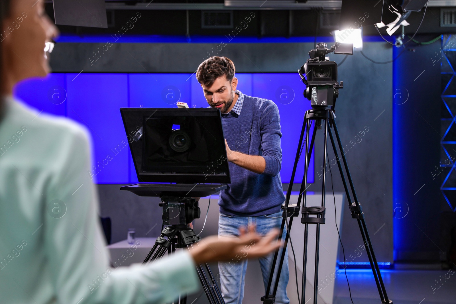 Photo of Presenter and video camera operator working in studio. News broadcasting