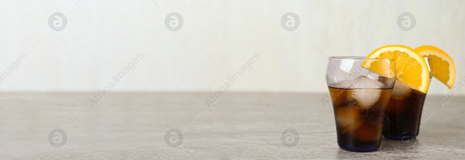 Photo of Delicious cocktails with orange and ice balls on grey table, space for text