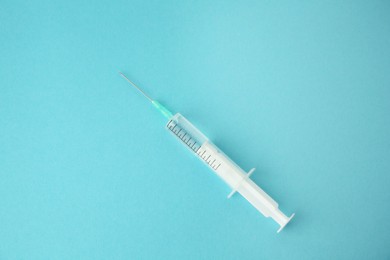 Photo of Medical syringe on light blue background, top view