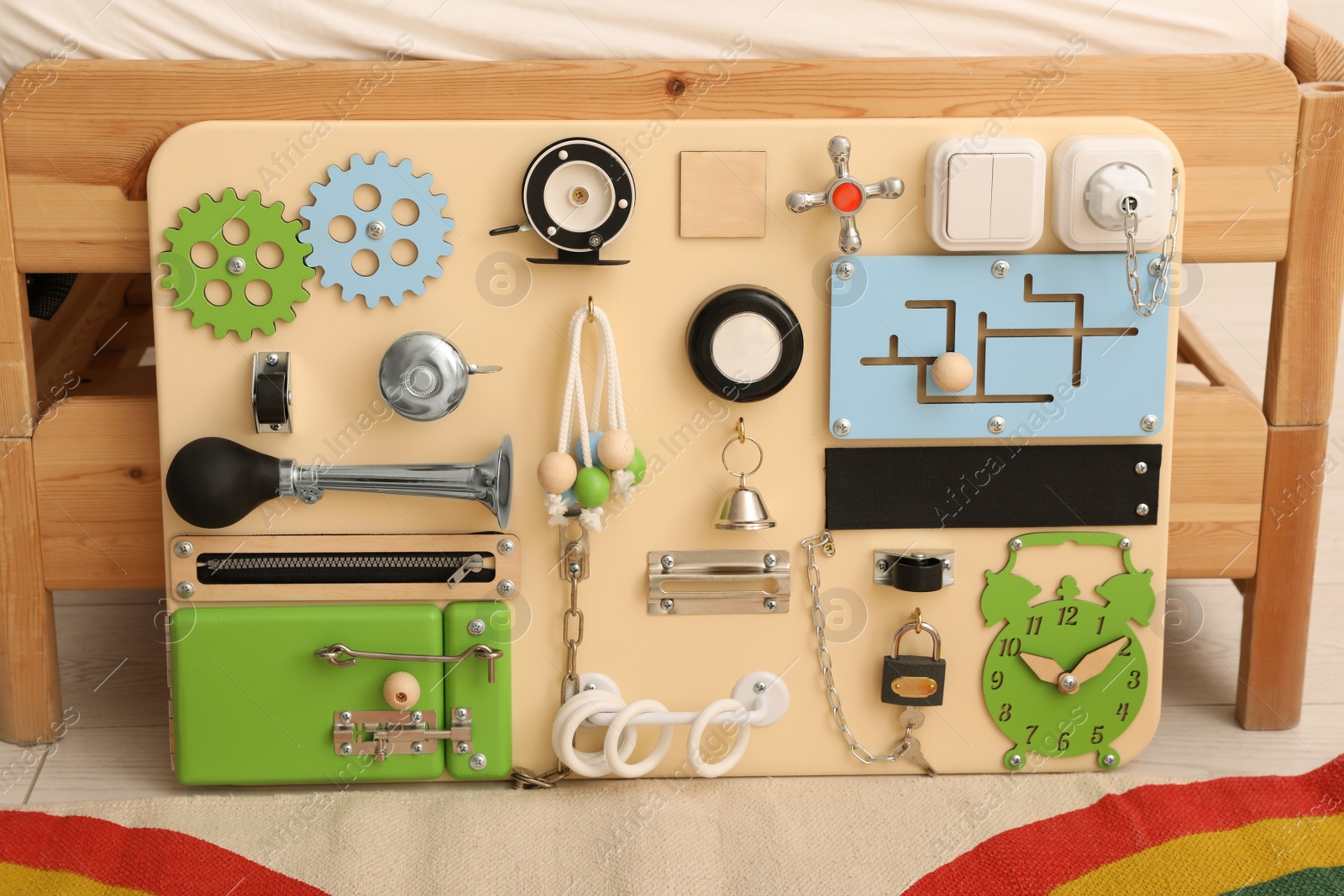 Photo of Busy board on floor near bed indoors. Baby sensory toy