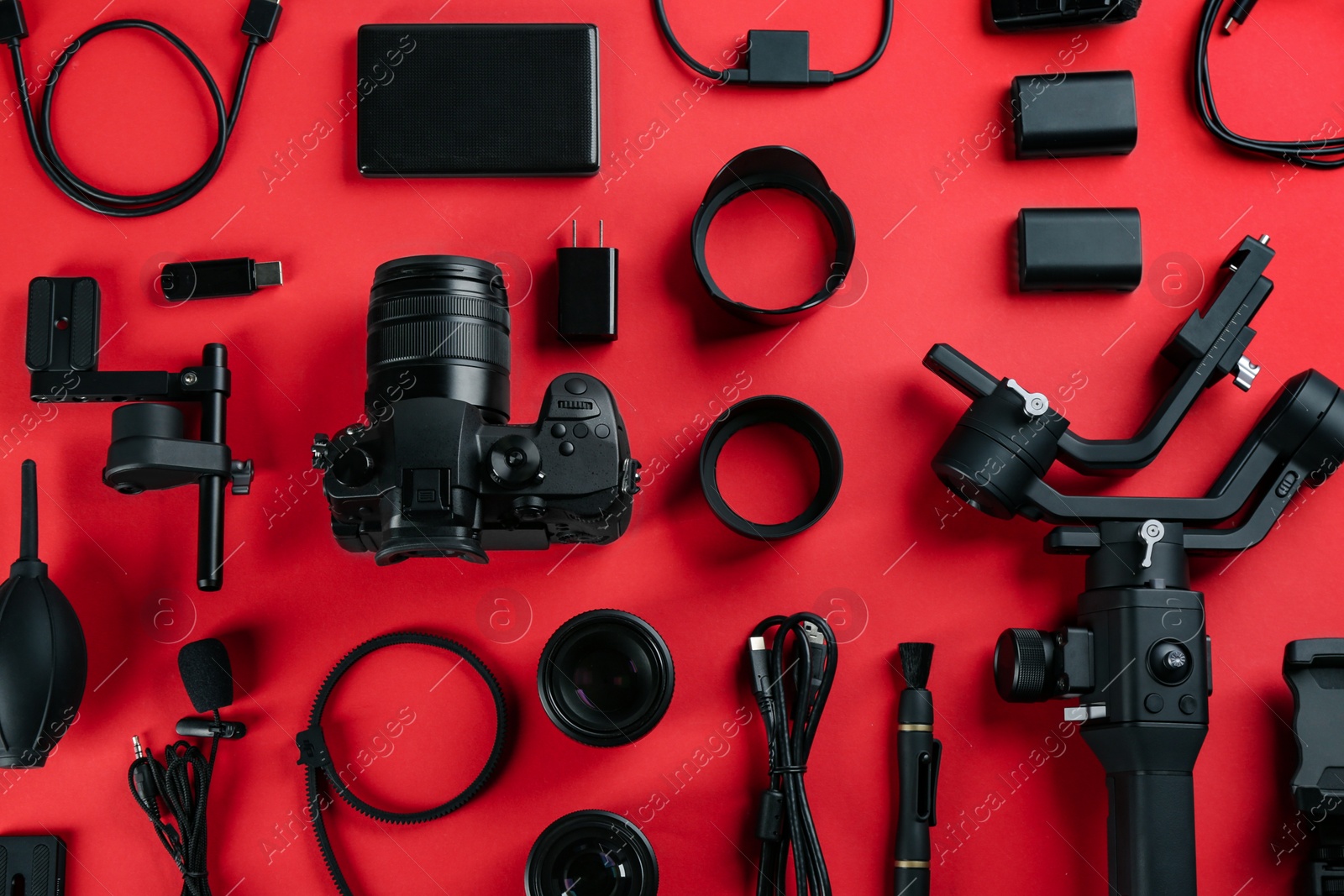 Photo of Flat lay composition with camera and video production equipment on red background