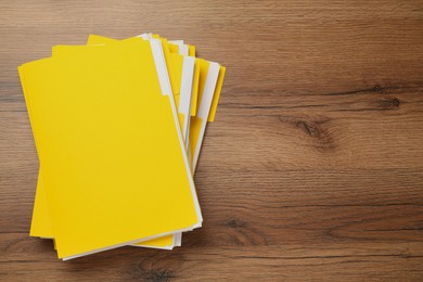 Photo of Yellow files with documents on wooden table, top view. Space for text