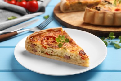 Photo of Piece of delicious homemade vegetable quiche on light blue table, closeup