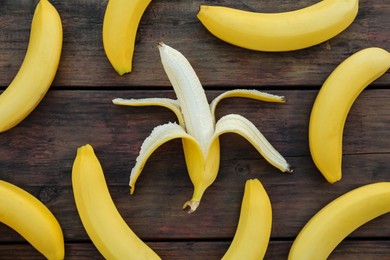 Photo of Many delicious yellow bananas on wooden table, flat lay