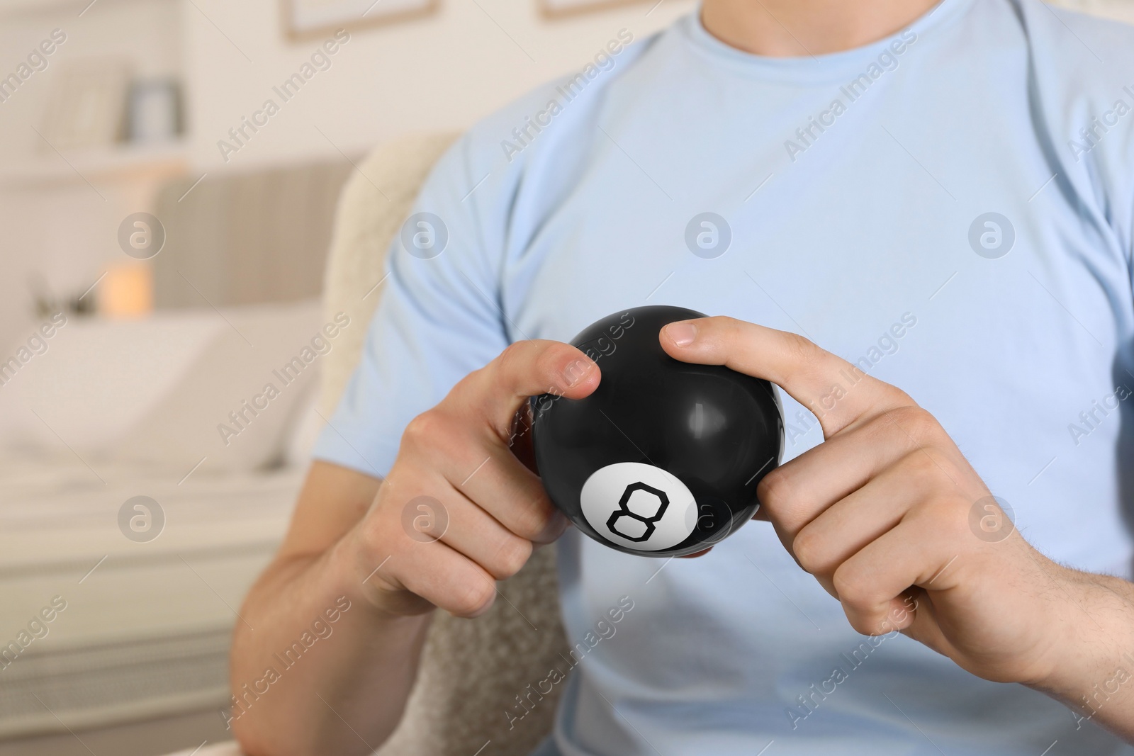 Photo of Man holding magic eight ball indoors, closeup