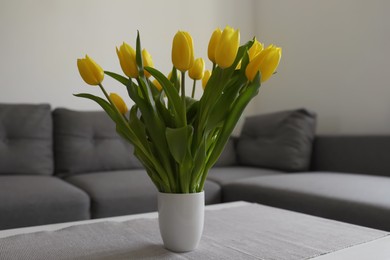 Bouquet of beautiful yellow tulips on table in living room