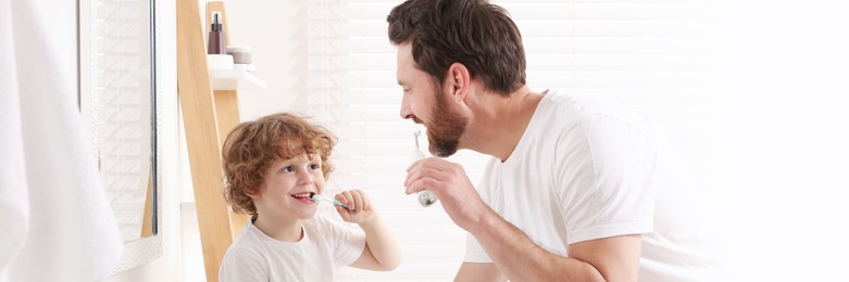 Father and his son brushing teeth together in bathroom. Banner design