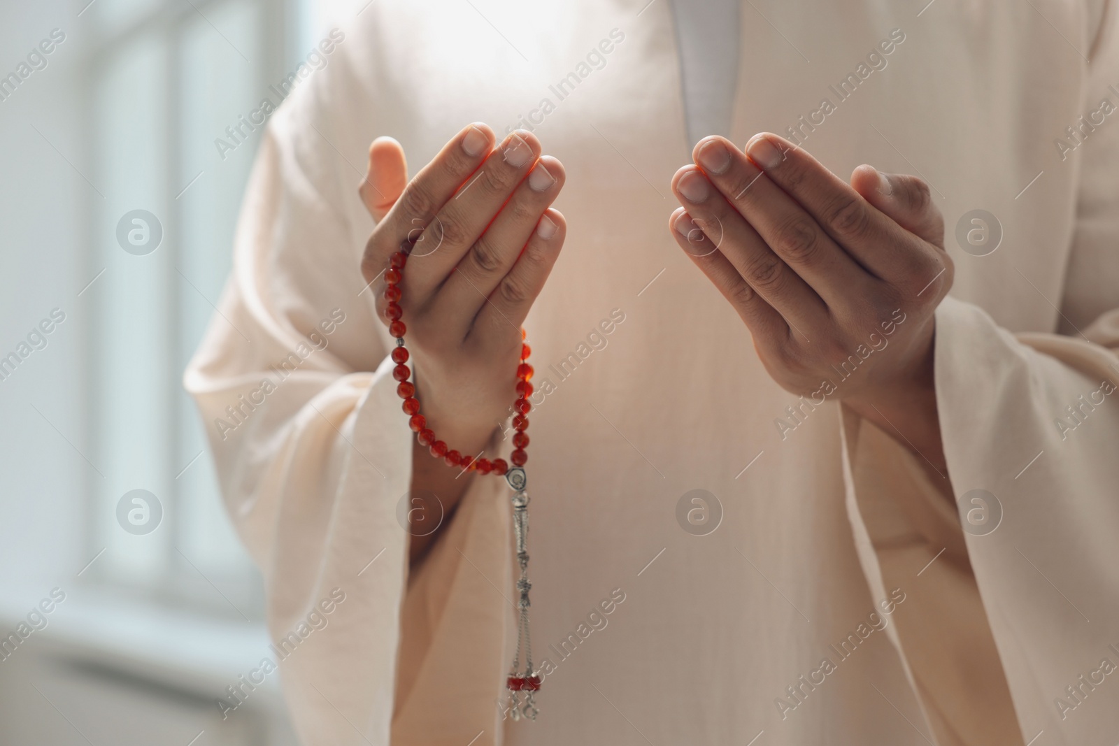 Photo of Muslim man with misbaha praying indoors, closeup