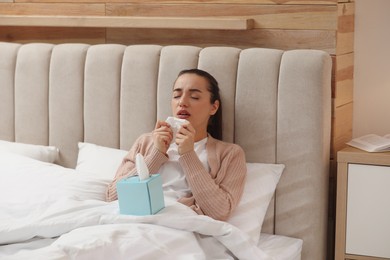 Photo of Sick young woman with napkins in bed at home