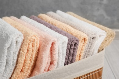 Photo of Laundry basket with clean terry towels on floor, closeup