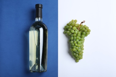 Fresh ripe juicy grapes and bottle of wine on color background, flat lay