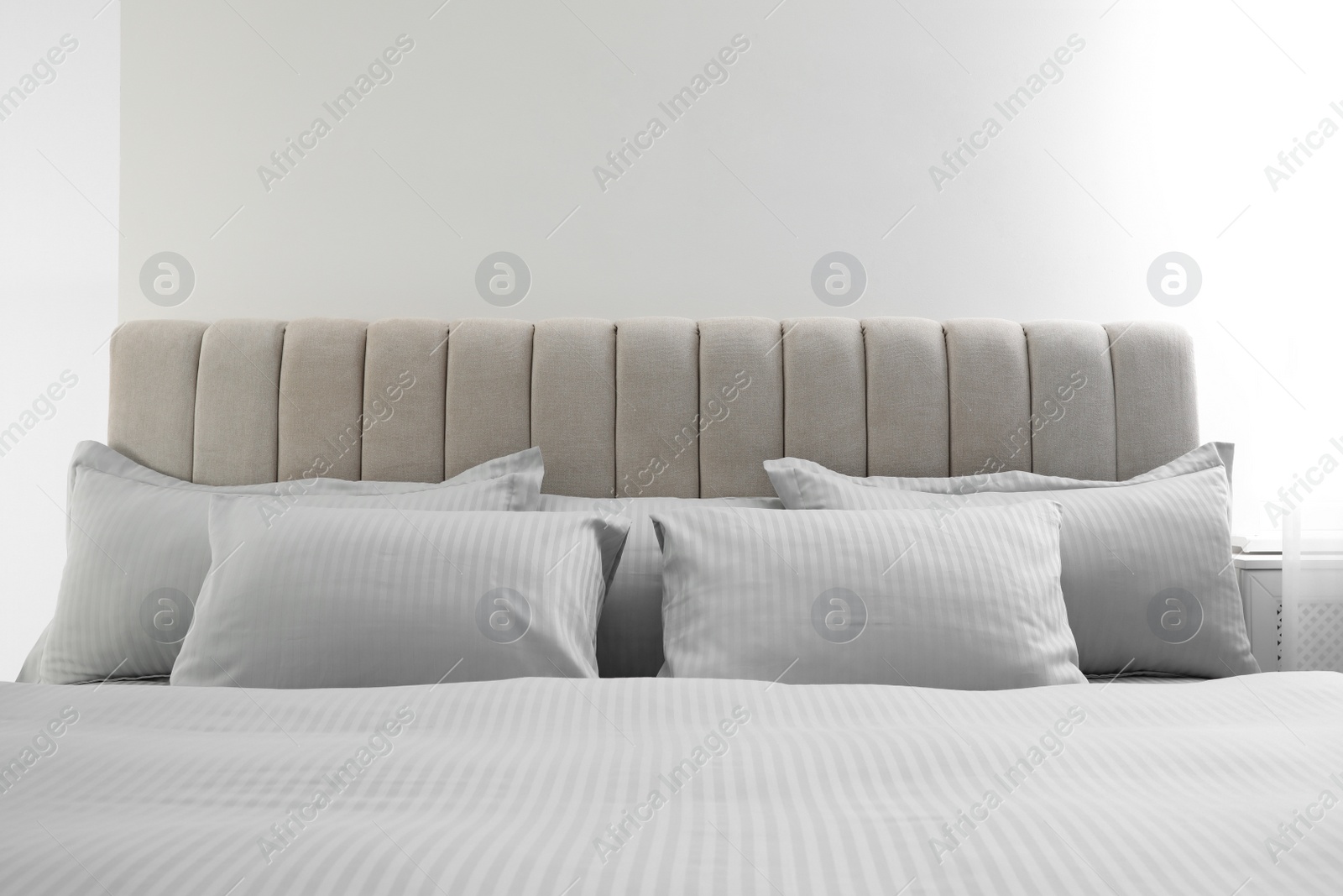 Photo of Many soft pillows and blanket on large comfortable bed indoors