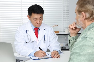 Photo of Doctor consulting senior patient at white table in clinic
