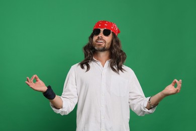 Stylish hippie man in sunglasses on green background