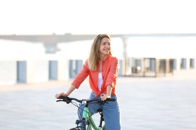 Photo of Young woman riding bicycle in city on sunny day